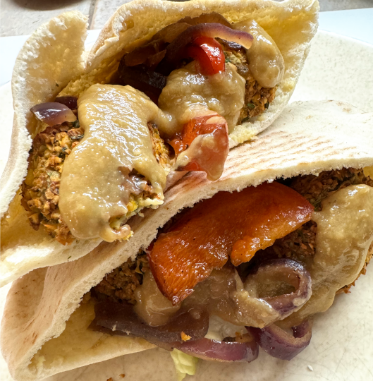 Falafel Sandwich with Tahini Sauce, grilled peppers and onions, and hummus in a pita pocket