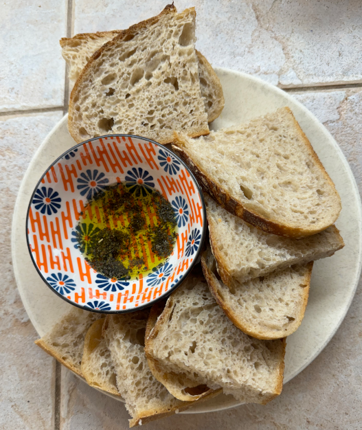 Rustic Sourdough sliced and plated with olive oil and herbs.