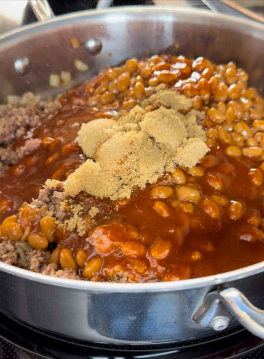 Spices, baked beans, and BBQ sauce added to the pan