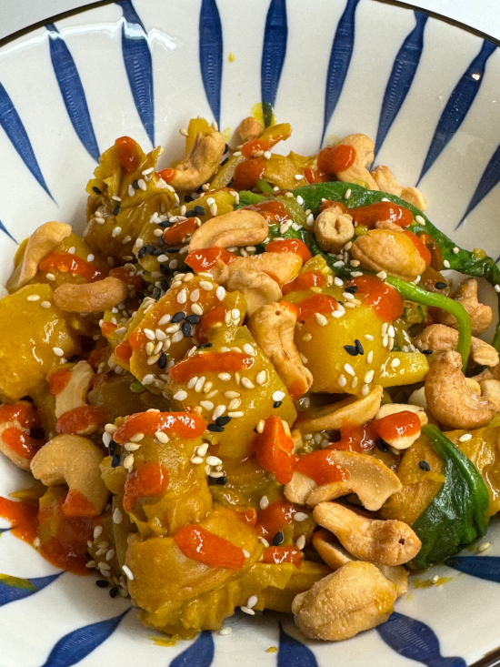 Yellow Curry Tofu Knots with Spinach, Potatoes, and Carrots topped with Sesame Seeds, Cashews, and Sriracha