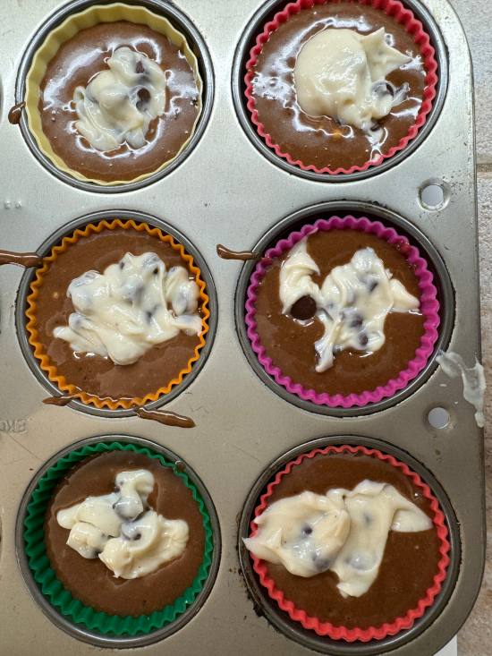 Cupcakes with cream cheese and batter ready to be baked