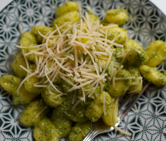 Baked pesto gnocchi topped with vegan parmesan cheese