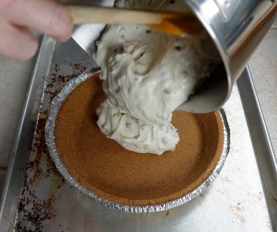 Adding the pie shell with the caramel chip cheesecake filling