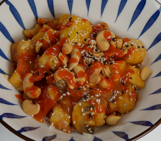 Sweet and Sour Tofu topped with cashews, sesame seeds, and sriracha over jasmine rice