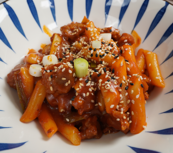 Spicy rice cakes with seitan and topped with sesame seeds and green onions