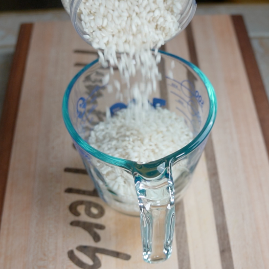 Measuring Arborio rice for the meal in a measuring cup