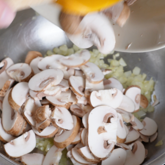 Adding the sliced mushrooms to the skillet