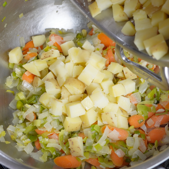 Adding the parboiled potatoes to the pan