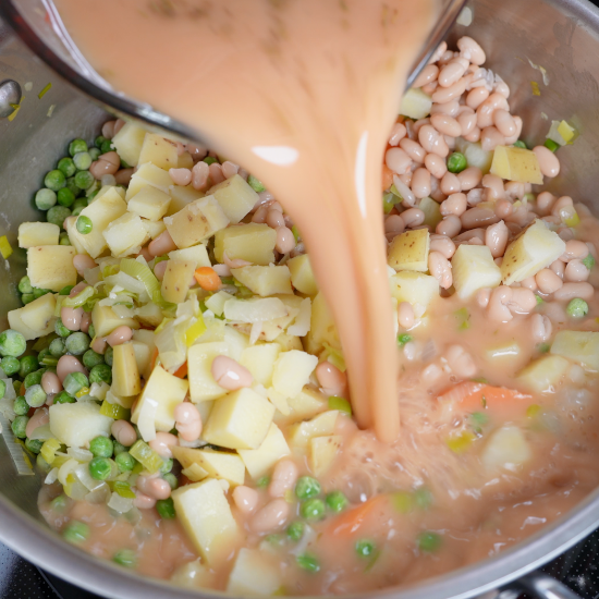 Prepared veggie stock being added to the skillet