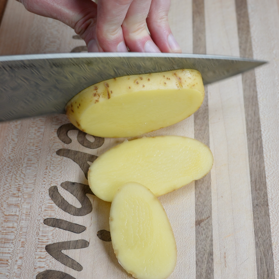 Preparing the Yukon gold potatoes by first slicing into medium sized pieces before dicing.