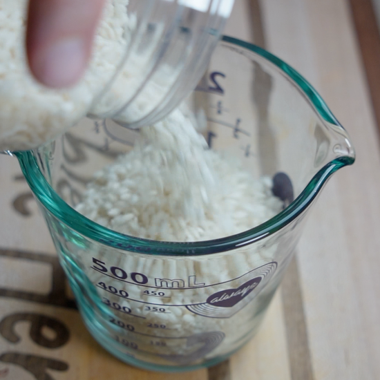 Measuring Arborio rice in a measuring cup
