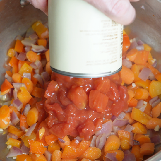 Adding diced tomatoes to the skillet